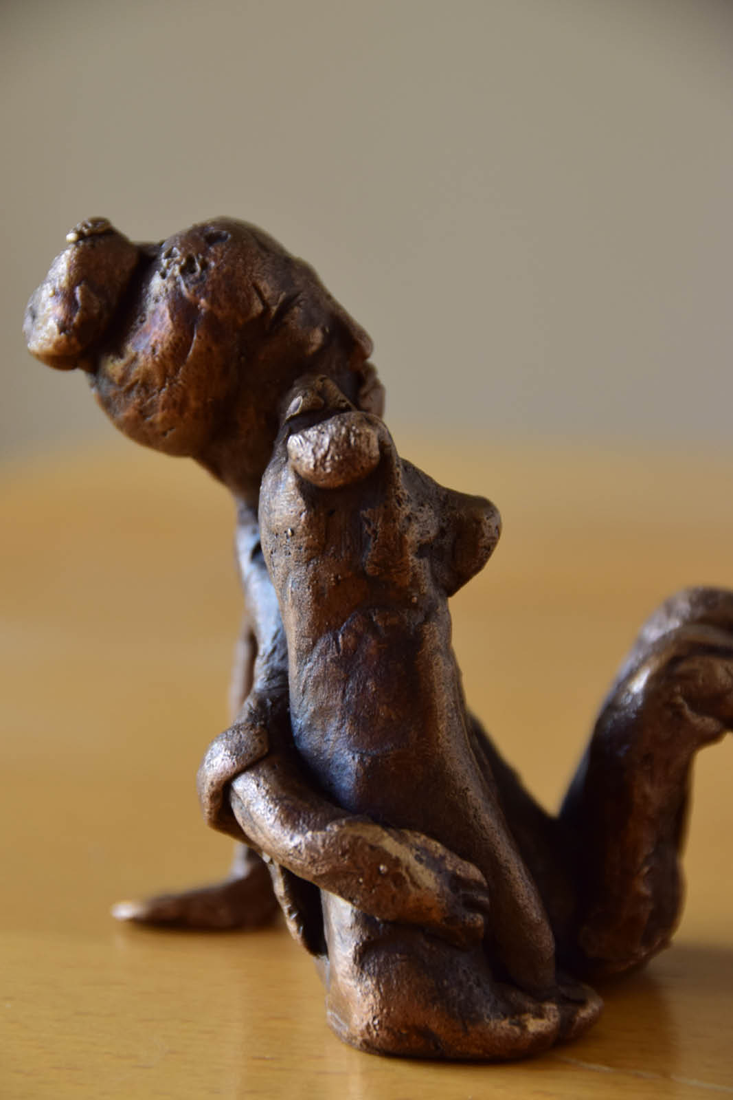 Skulpturen. Bronzeskulptur einer sitzenden Frau mit einem Hund. Die Abbildung zeigt das Paar von der Seite.