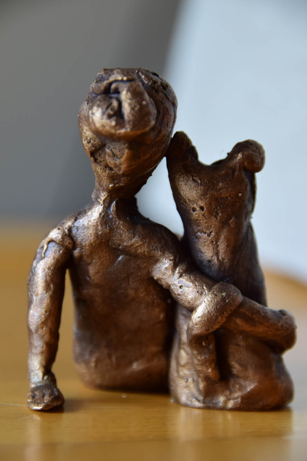 Skulpturen. Bronzeskulptur einer sitzenden Frau mit einem Hund. Die Abbildung zeigt das Paar von hinten.