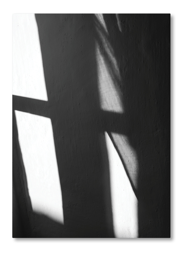 Abstraktes Zusammenspiel von Licht und Schatten auf einer Wand mit geometrischen Formen und sanften Kontrasten.