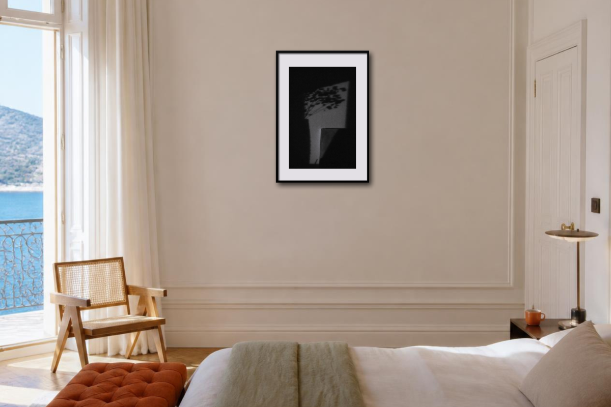 Gerahmter Fine-Art-Print mit abstrakten Licht- und Schattenformen an einer Wand in einem hellen Schlafzimmer.